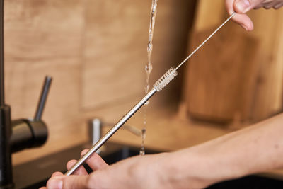 Woman cleaning metal straw with organic brush. zero waste concept