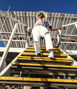 Low angle view of woman moving down on staircase against sky