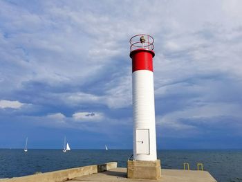 Lighthouse by sea against sky