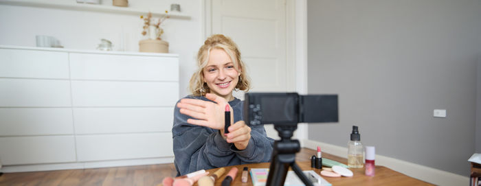 Portrait of young woman using mobile phone while standing at home