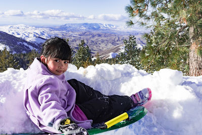 Woman sitting on snow covered mountains during winter