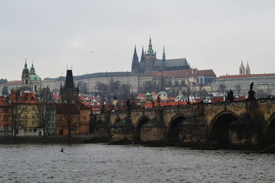 Bridge over river against buildings in city