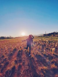 Rear view of woman standing on field against clear sky