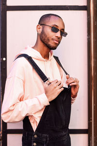 Young man wearing sunglasses while standing against closed door