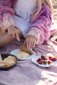 Woman cutting fresh pie and pears having picnic at sandy sea shore outdoors. summer time.