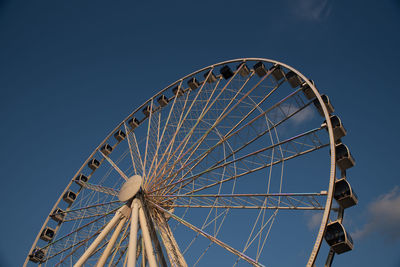 Low angle view of ferris wheel against blue sky