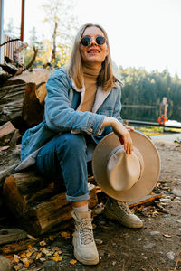 Portrait of young woman wearing sunglasses sitting outdoors