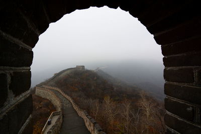 Walkway at great wall of china during foggy weather seen through arch