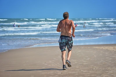 Rear view of shirtless man on beach