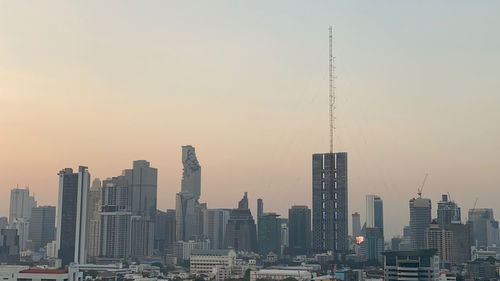 Modern buildings in city against sky during sunset