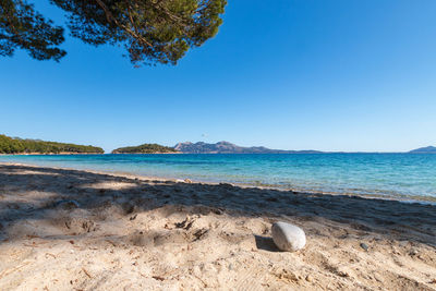 Scenic view of beach against clear blue sky