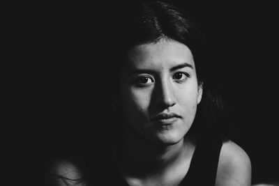 Close-up portrait of woman against black background