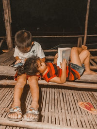 Rear view of friends sitting on wood