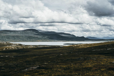 Scenic view of landscape and mountains against cloudy sky