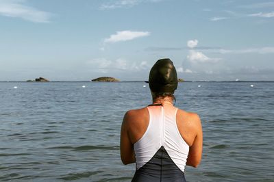 Rear view of mature woman standing in sea against sky