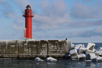 Lighthouse by sea against sky