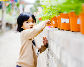 Portrait of cute girl standing by potted plants