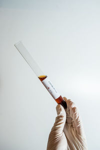 Close-up of hand holding cigarette against white background