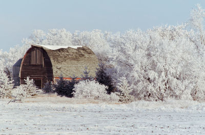 Snow covered land by building against sky