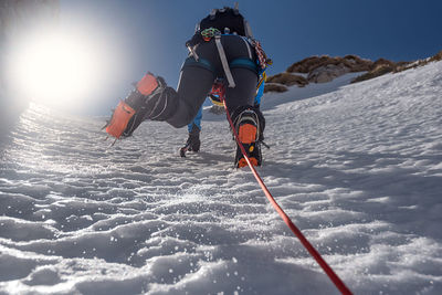 Low angle view of woman climbing snow covered mountain