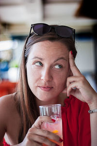 Portrait of young woman drinking from glass at restaurant