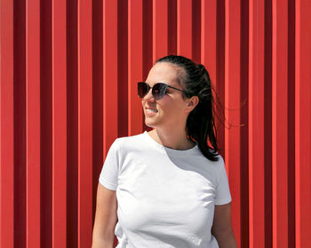 Portrait of a happy young woman in white t-shirt on red backgdrop.