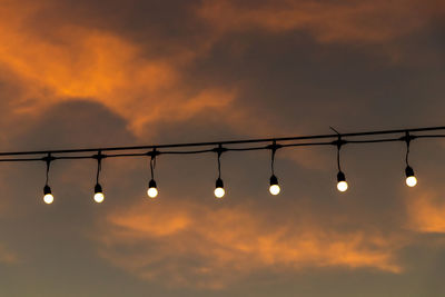 Low angle view of illuminated lights against sky during sunset