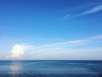 Scenic view of blue sea against cloudy sky on sunny day