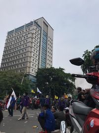 People on street by buildings against sky