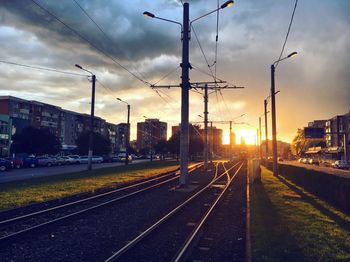 Railroad tracks in city against sky during sunset