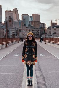 Portrait of smiling young woman standing on bridge in city
