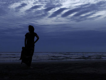 Silhouette man standing on beach against sky