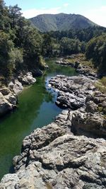 Scenic view of river by mountains against sky