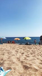 Group of people on beach against clear sky