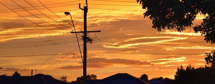 Silhouette electricity pylon against sky during sunset