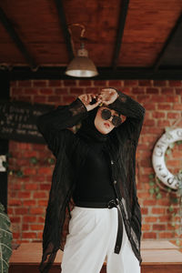 Portrait of woman standing against brick wall