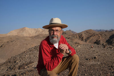 Senior man in red sitting in the desert 