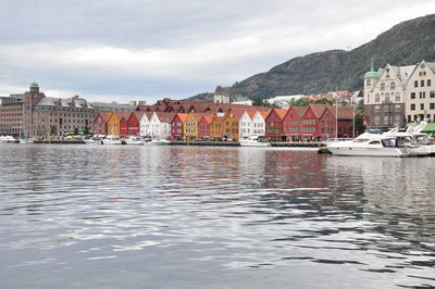 Buildings at waterfront against cloudy sky