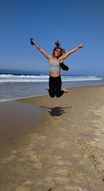 Full length of woman standing at beach against sky