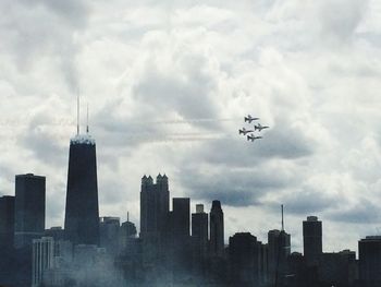 Low angle view of skyscrapers against cloudy sky