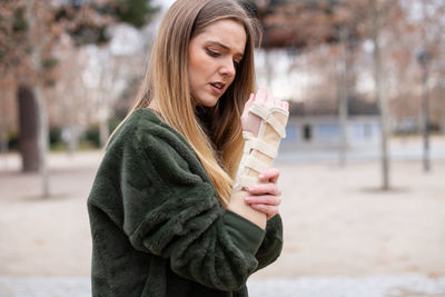 Young woman with fractured hand standing on street