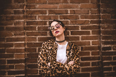 Portrait of young man standing against brick wall