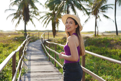 Portrait of young woman standing against trees