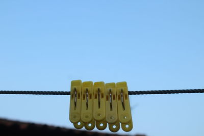 Close-up of clothespins on rope against clear blue sky
