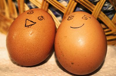 Close-up of anthropomorphic smiley faces drawn on brown eggs