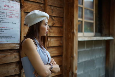 Woman looking away while standing against wall