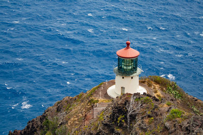 Lighthouse by sea against sky