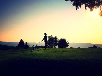 Silhouette man standing on golf course against clear sky