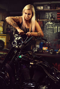 Woman repairing motorcycle at workshop