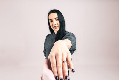 Portrait of young woman sitting against white background
